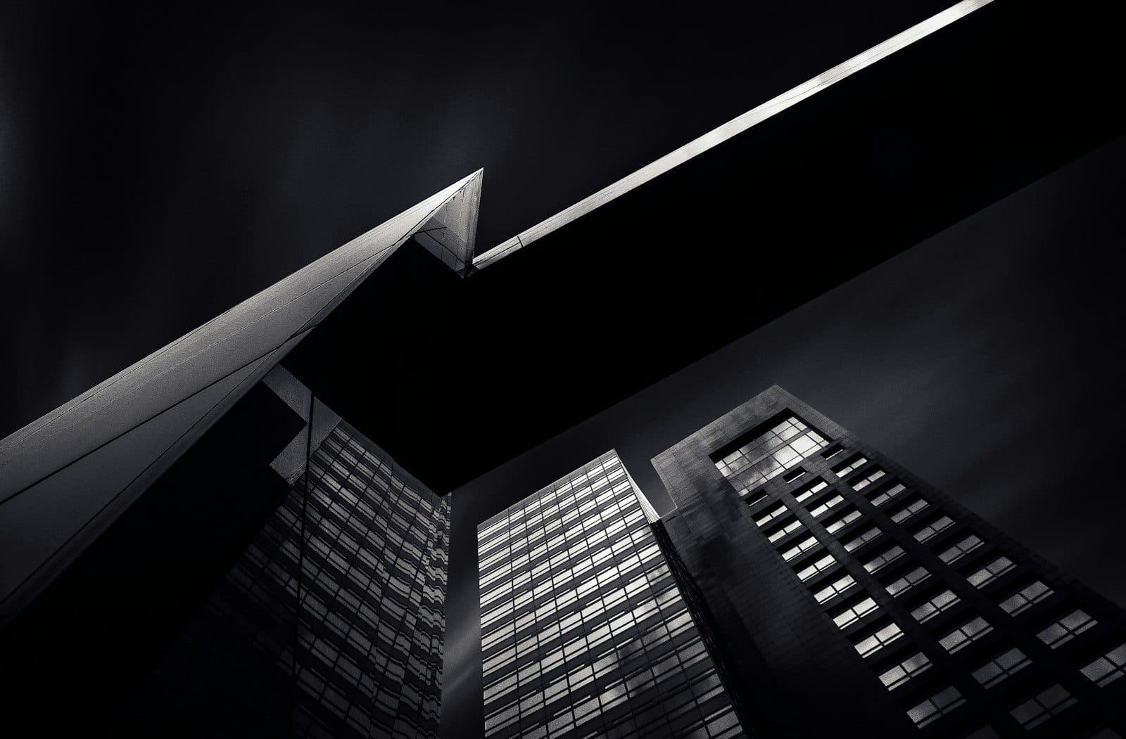 A dark wedge-shaped building against towers at dusk